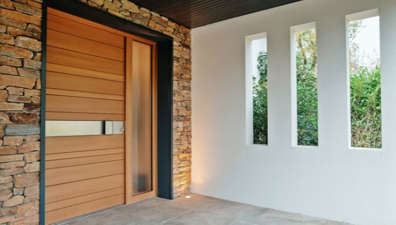 porte d'entrée sur mesure en bois sur une maison moderne avec parement de pierre