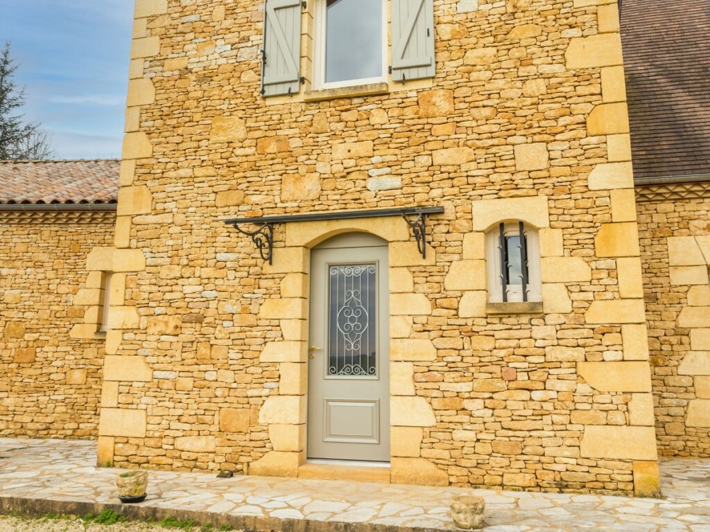 une maison en pierre jaunes avec une porte d'entrée avec cintrage