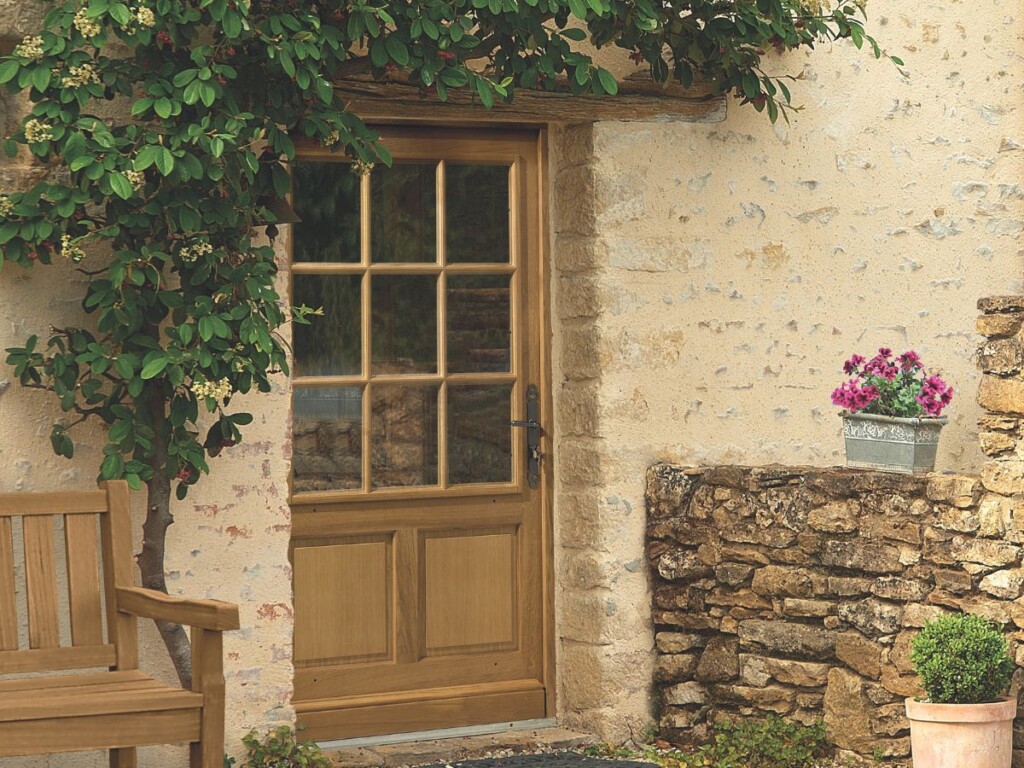 maison de campagne avec une porte d'entrée en bois avec des petits bois collés sur le vitrage