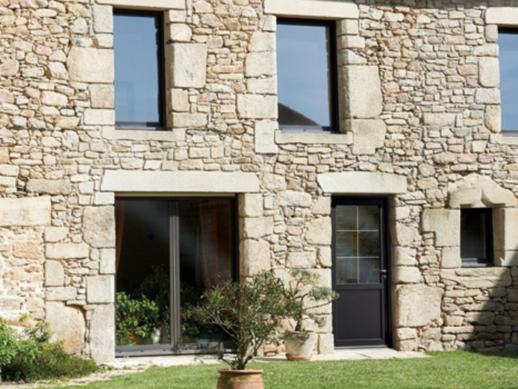 une maison en pierre avec une porte d'entrée avec des petits bois collés style campagne